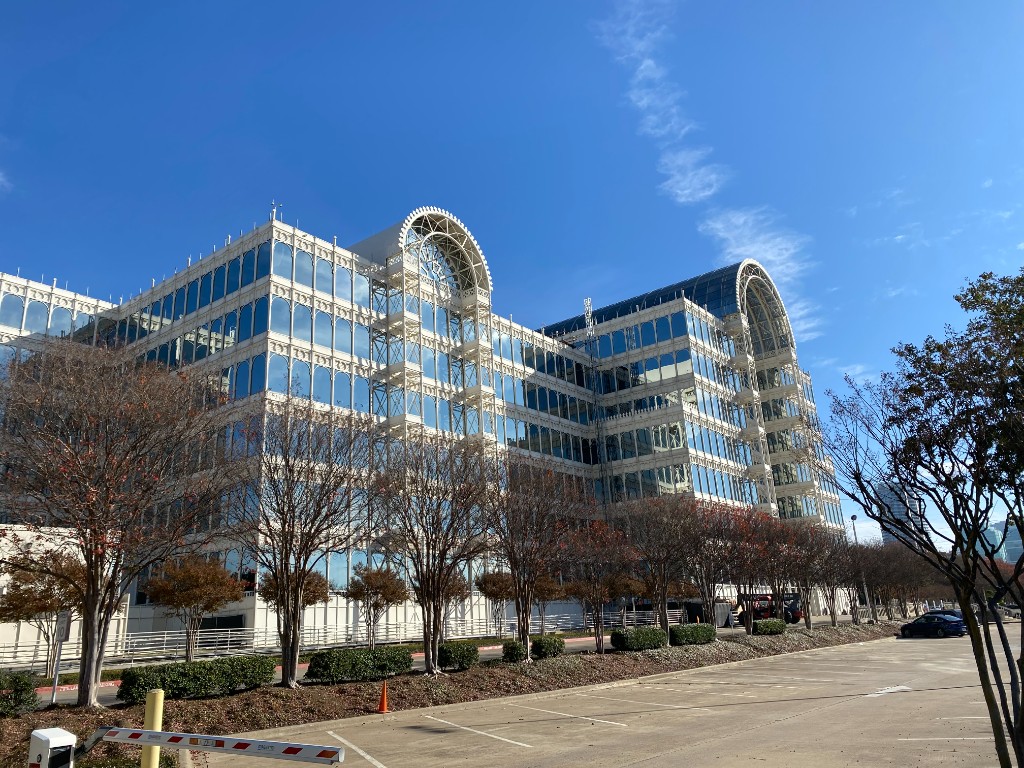 The Infomart building exterior in Dallas, Texas, a distinctive glass and steel structure housing ColossusCloud's data center